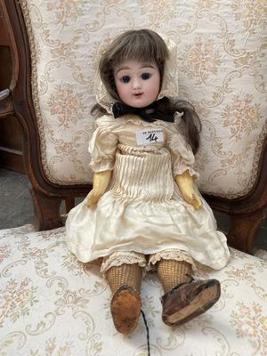 une poupée assise sur une chaise dans une pièce