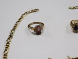 two gold rings and a necklace are on a white surface