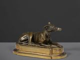 une statue en bronze représentant un chien couché sur un livre
