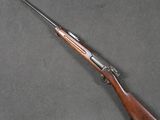 a rifle with a wooden barrel and a wooden handle on a gray surface