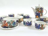 plusieurs tasses et soucoupes, ainsi qu'une théière et sa soucoupe, posées sur une table blanche