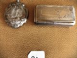 two small silver objects are sitting next to each other on a brown leather surface