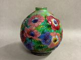 un petit vase sur lequel sont peintes des fleurs sur fond blanc