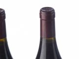 four bottles of wine are lined up on a white surface