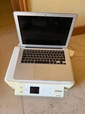 un ordinateur portable posé sur une imprimante, par terre