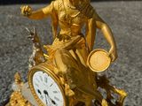 une statue en or représentant une femme, avec une horloge posée sur une table