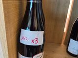 une bouteille de vin posée sur une étagère à côté de deux bouteilles de vin
