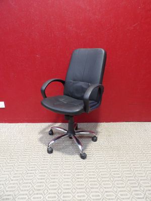 une chaise de bureau noire placée devant un mur rouge