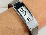 a wrist watch on a woman ' s wrist with a leather band