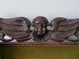 a green chair with a carved head and wings on it