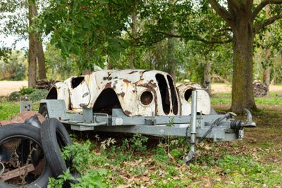 a rusted out old car sitting in the grass