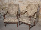 two chairs sitting next to each other in front of a stone wall