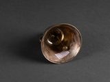 brass bell on a black surface with a label on it