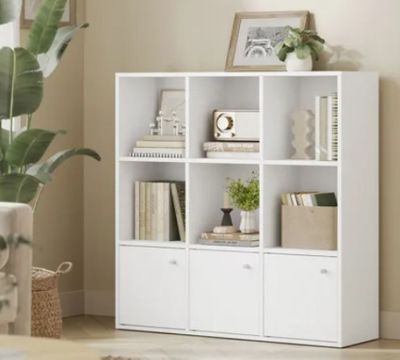 a white bookcase with many books on it in a living room