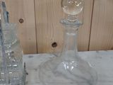 a glass bottle and a glass candle holder on a marble table