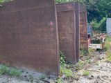 a rusted metal fence on the side of a dirt road
