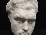 a white sculpture of a man ' s head on a black surface