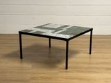 une petite table avec un plateau en carrelage posée sur un parquet