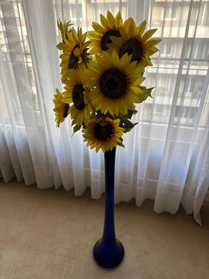 des tournesols jaunes dans un vase bleu devant une fenêtre