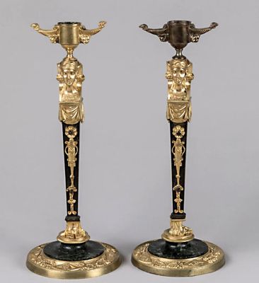 une paire de bougeoirs noirs et dorés ornés de figures