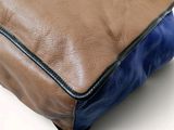 a brown and blue purse sitting on a white surface