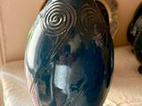 un vase bleu posé sur un lit, à côté d'un autre vase bleu