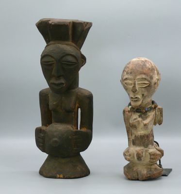 Deux figurines africaines sont assises l'une à côté de l'autre sur une surface blanche