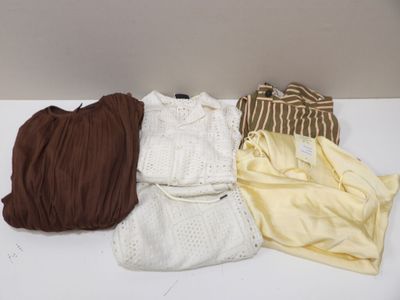 Quatre vêtements sont disposés sur une table blanche