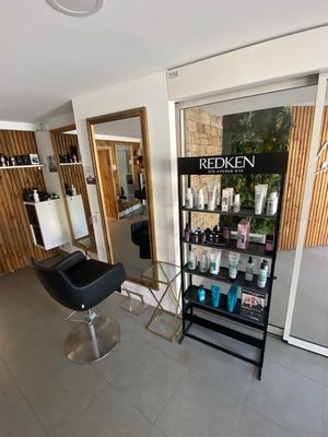 une photo d'un salon de coiffure avec un sèche-cheveux et des fauteuils