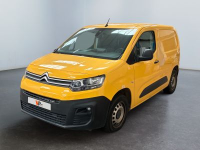 La camionnette jaune est garée dans une grande pièce au sol noir.