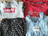 three t - shirts and a skirt sitting on a cardboard box