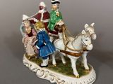 a figurine of a horse drawn carriage with people on it