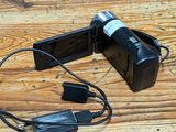 a video camera sitting on a wooden table with a charger