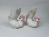 pair of white ceramic roosters with pink beaks on white background