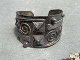 a silver bracelet and a silver ring on a table