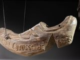 a wooden shoe hanging from a string with a sign on it