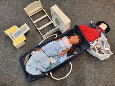 un bébé allongé dans une valise à côté d'une poupée