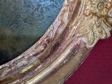 a mirror with a gold frame on a red surface