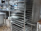 many trays of food sitting on a cart in the kitchen