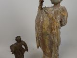 a statue of a woman holding a bird next to a figurine of a man