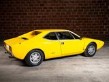 a yellow car that is parked in front of a brick wall