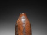 a brown vase sitting on top of a table next to a black background