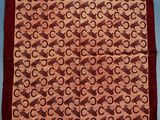 a brown and red square scarf with a pattern of circles on it