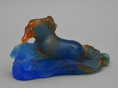 une figurine bleue et orange représentant un cheval au bord d'un plan d'eau
