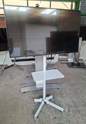 un grand téléviseur à écran plat posé sur un pied dans un entrepôt