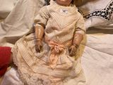 a doll that is sitting on a bed next to a pillow