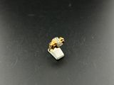 a close up of a white and gold ring on a black surface