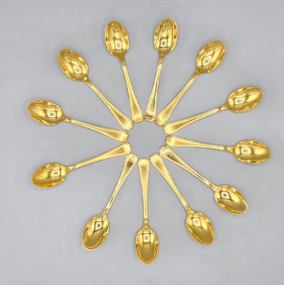 six gold spoons arranged in a circle on a white surface