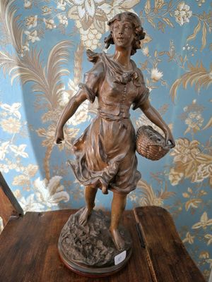 une statue représentant une femme tenant un panier posé sur une table