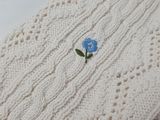 a white sweater with a blue flower on it
